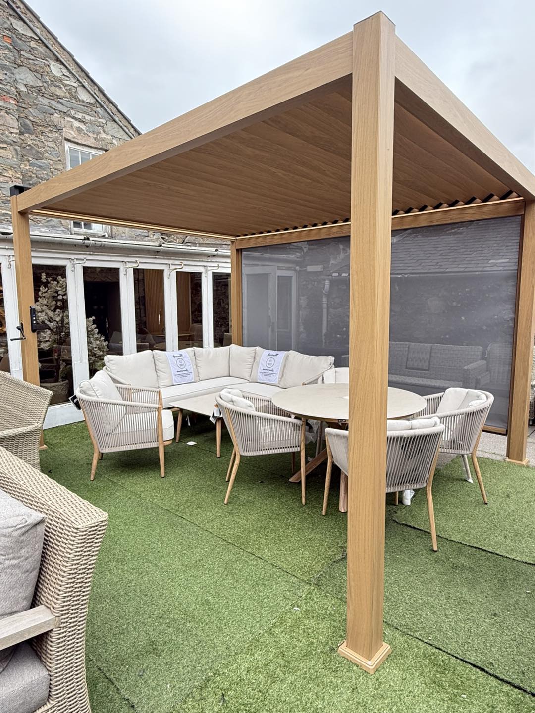 Outdoor patio area with wooden pergola, furniture, and green grass.