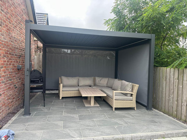 Apergola installed by Jacksons of Saintfield and Jacksons of Moira in Northern Ireland.  Outdoor patio area with a pergola, sectional sofa, and table on a paved patio.