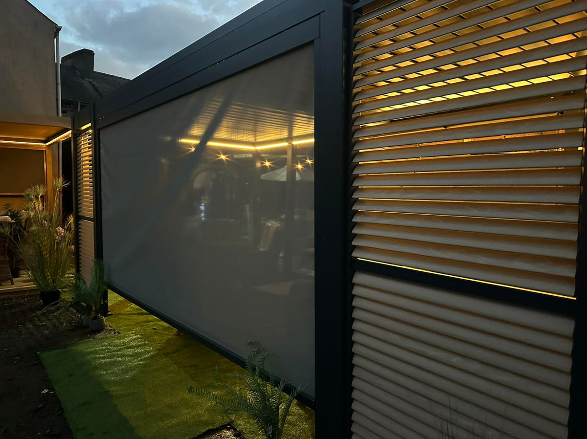 Outdoor setting with a pergola at Jacksons of Moira with a large screen and wooden slat wall at night.