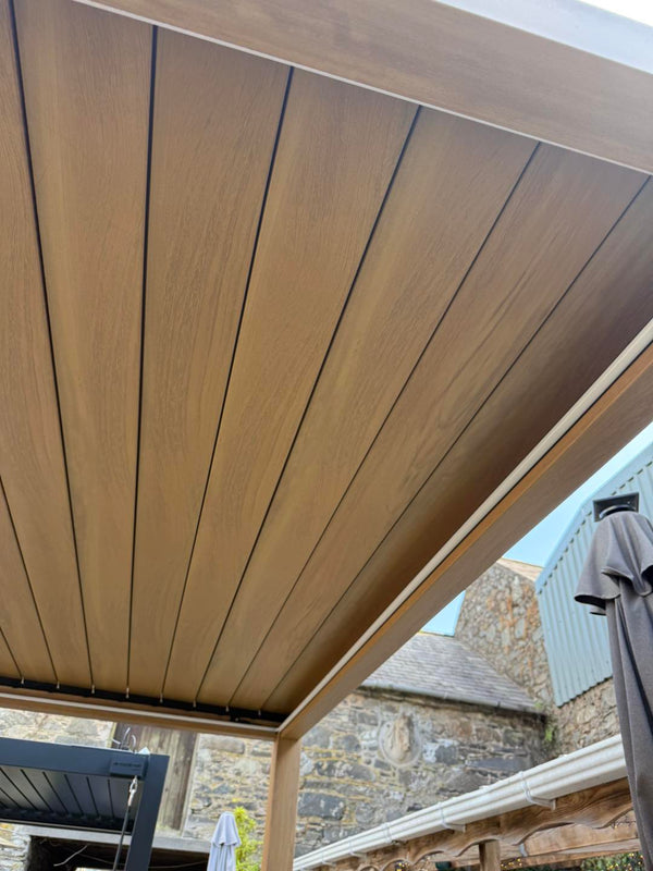 Wooden pergola structure at Jacksons of Saintfield with a stone building in the background